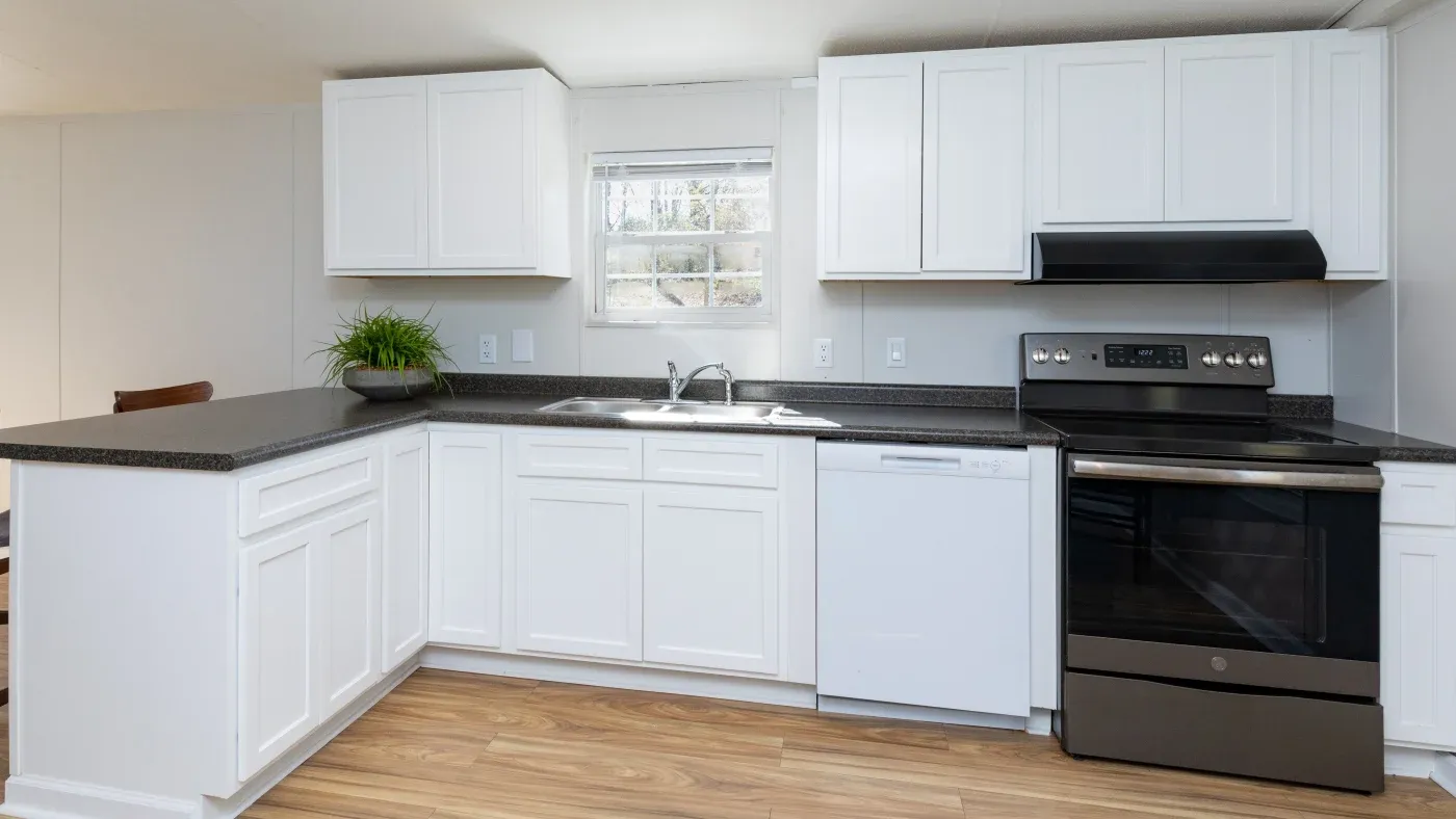 An open kitchen with white cabinets and black countertops